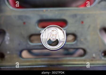 Vue de haut en bas montrant une boîte de boisson en aluminium vide ouverte reposant sur un fond métallique industriel donnant une sensation négligée de déchets et de pol Banque D'Images