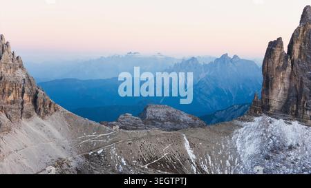 Vue aérienne de Tre Cime di Lavaredo avec des pics rocheux dentelés et des pentes enneigées sous un ciel crépusculaire doux Auronzo di Cadore, Vénétie, Italie. Banque D'Images