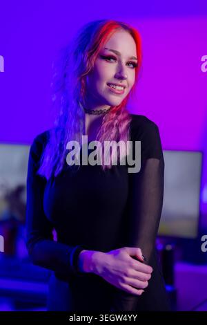 Jeune femme avec des cheveux vibrants dans un éclairage de studio violet ambiant Banque D'Images