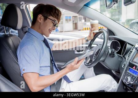 Homme d'affaires souriant utilisant la tablette dans sa voiture Banque D'Images