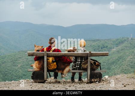 Couple de voyageurs assis avec deux chiens Berger allemand et australien sur un banc de montagne en Serbie. Vue arrière. Concept d'amitié, randonnée Banque D'Images