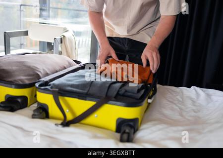 Emballer les vêtements dans la valise jaune sur la préparation de voyage de lit Banque D'Images