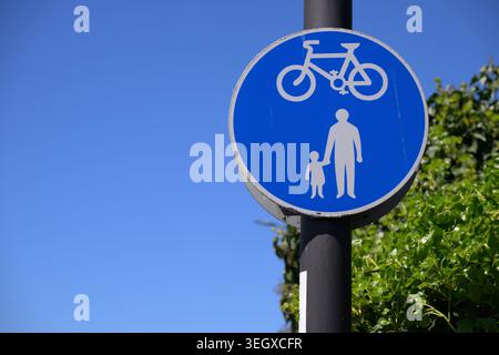 Panneau bleu partagé pour piétons et pistes cyclables à Enfield Island Village contre le ciel dégagé avec feuillage vert et espace de copie. Banque D'Images