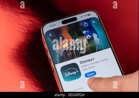 New York, États-Unis - 5 mai 2026 : ouvrez l'application de plate-forme Disney plus sur l'écran de smartphone iphone vue rapprochée sur fond de feuille rouge Banque D'Images