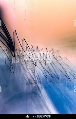 Art photographique conceptuel avec des lignes noires angulaires et de fines traînées créées par le mouvement de la caméra sur un fond dégradé bleu et pêche. Banque D'Images