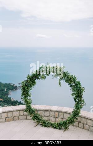 Vue sur l'océan tranquille avec décoration verte circulaire sur la surface en pierre pour une petite cérémonie de mariage Banque D'Images