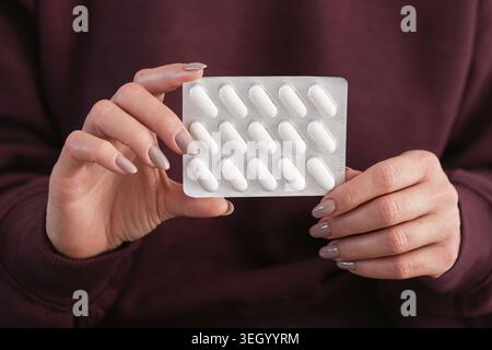 Femme tenant le paquet blister avec des pilules blanches en gros plan. Médicament pharmaceutique et concept de traitement de santé avec comprimés médicaux à l'intérieur. Banque D'Images