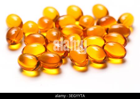 Capsules de gel doré isolées sur fond blanc en gros plan. Suppléments pharmaceutiques et concept de médicaments de soins de santé avec des vitamines oméga. Banque D'Images