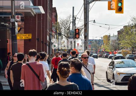 Toronto, Ontario, Canada - 17 mai 2026 : foule de piétons traversant un passage pour piétons sur la rue Queen au centre-ville de Toronto avec signal de compte à rebours, rouge h Banque D'Images