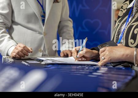 Signature du formulaire d'inscription à la conférence médicale. Gros plan de professionnels signant des documents à un bureau d'inscription à un événement de soins de santé avec BLUE Medical Banque D'Images