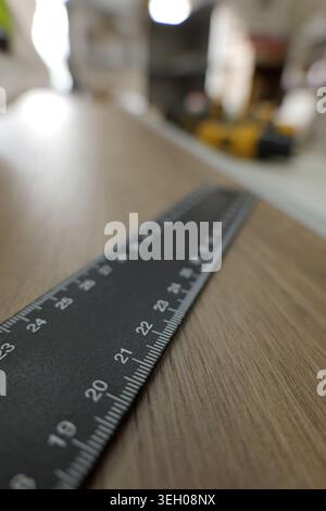 Règle en métal noir sur surface en bois, gros plan montrant des marquages centimétriques et une mesure précise pour le travail du bois, la menuiserie et les projets de bricolage avec Sha Banque D'Images