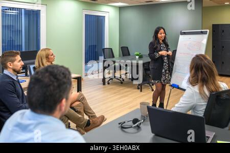 Femme hispanique confiante dirigeant une présentation d'affaires à l'aide du tableau blanc dans la réunion Banque D'Images