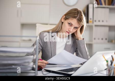 Femme d'affaires fatiguée travaillant avec des documents au bureau Banque D'Images