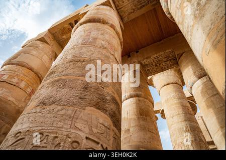 Vue spectaculaire vers le haut à faible angle des colonnes de grès imposantes recouvertes de hiéroglyphes anciens et de sculptures en relief colorées à l'intérieur du Grand Hypostyl Banque D'Images