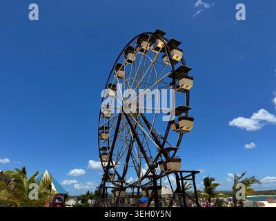 Grande grande roue noire debout contre un ciel bleu vif avec des nuages blancs clairs par une journée ensoleillée à CABO ROJO Banque D'Images