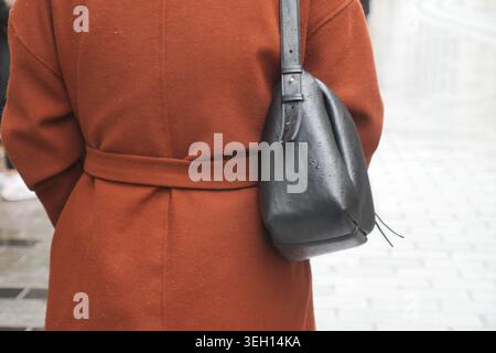 Femme marche dans la rue de la ville en manteau brun avec sac noir Banque D'Images