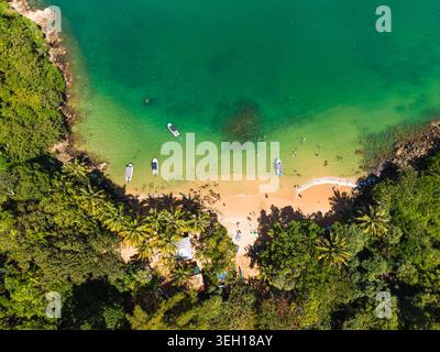 Vue aérienne de Jungle Beach avec des eaux turquoises, de petits bateaux ancrés près du rivage et une végétation tropicale luxuriante à Unawatuna, au Sri Lanka. Banque D'Images