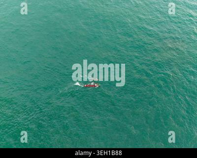 Vue aérienne d'un petit bateau de pêche traditionnel avec des pêcheurs se déplaçant à travers la mer turquoise à Galle, Province du Sud, Sri Lanka. Banque D'Images