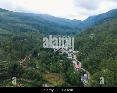 Vue aérienne du village de Nallathanniya niché dans une vallée verdoyante entourée de plantations de thé et de montagnes brumeuses à Nallathanniya, Central Banque D'Images