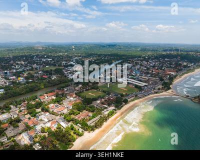Vue aérienne de la rivière Nilwala qui coule à travers le paysage urbain et la verdure luxuriante vers la plage de sable et l'océan turquoise à Matara, sud Banque D'Images