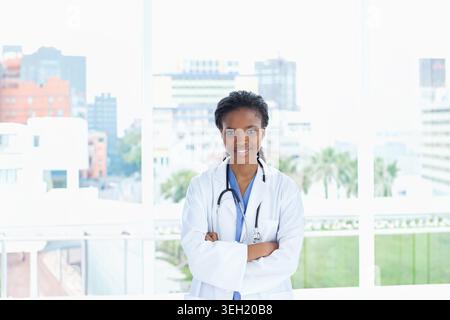 Médecin afro-américain debout centré dans la clinique portant une blouse de laboratoire blanche et un stéthoscope Banque D'Images