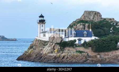 Vue aérienne de l'île de Louet avec le phare historique et le chalet blanc perché sur des falaises rocheuses entourées par la mer à Carantec, Bretagne, F. Banque D'Images
