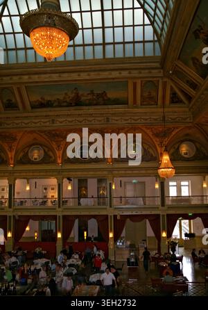 SCHEVENINGEN, LA HAYE, PAYS-BAS - 27 JUIN 2007 : visiteurs à l'intérieur du hall historique de l'hôtel Kurhaus avec lustres, toit en verre et interio peint Banque D'Images