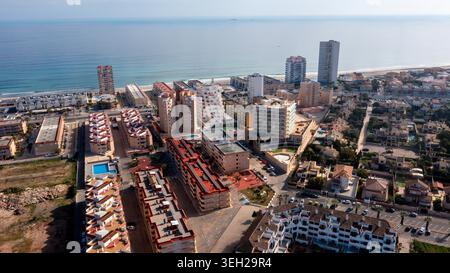 La Manga del Mar Menor - Murcie - Espagne - 2026 : cette vue aérienne montre des immeubles d'appartements, des hôtels, des rues et des piscines à côté d'un front de mer calme, avec la mer à travers l'horizon dans la brume. Banque D'Images