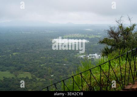 Vue sur le paysage verdoyant de la jungle et un lac calme vu d'un point de vue élevé avec des montagnes brumeuses sous un ciel couvert Sigiriya, Pr central Banque D'Images