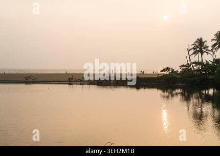 Vue des bateaux traditionnels et des gens sur une plage de sable par l'eau calme au coucher du soleil Galle, Province du Sud, Sri Lanka. Banque D'Images