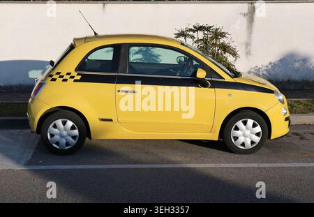 Udine, Italie. 5 mars 2023. Fiat 500 jaune avec une bande noire sur fond de mur blanc. Vue latérale. Banque D'Images