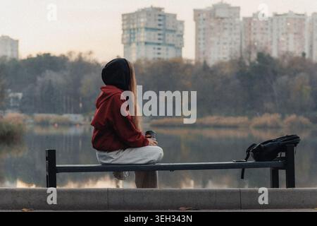La femme est assise tranquillement sur le banc du parc Banque D'Images