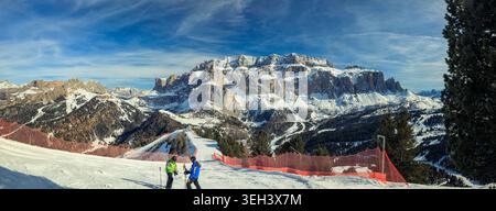 Sellaronda, Italie - 21.02.2025 : paysage panoramique grand angle de la chaîne de montagnes enneigée de Sellaronda dans les Dolomites italiennes. Deux skieurs STA Banque D'Images