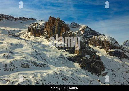 Marmolada, Italie - 22.02.2025 : une vue spectaculaire sur le massif de Marmolada, mettant en évidence les faces calcaires abruptes et les pentes enneigées sous un bleu clair Banque D'Images