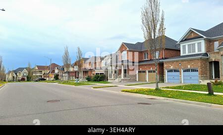Toronto, ON, Canada - 18 mai 2026 : vue d'une rue de banlieue avec une rangée de maisons individuelles bien entretenues un jour de printemps à Toronto, Canada. Banque D'Images