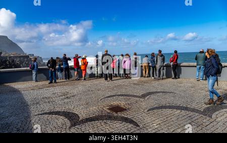 Portugal, Madère-2 février 2026 : les touristes se tiennent à un point de vue côtier à Porto Moniz regardant les puissantes vagues de l'Atlantique s'écraser contre Madeiras volca Banque D'Images