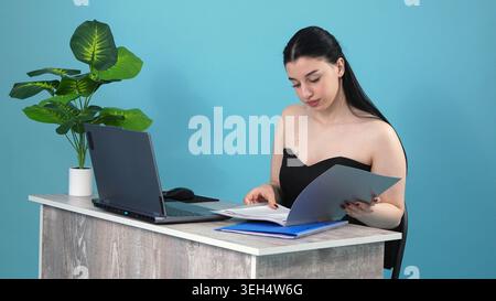 Jeune femme lisant des documents dans un bureau Banque D'Images