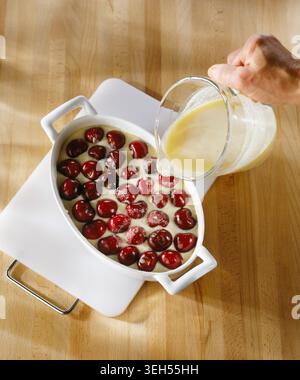 Verser le mélange d’amandes sur les cerises (recette de film : clafoutis cerise et amande) Banque D'Images
