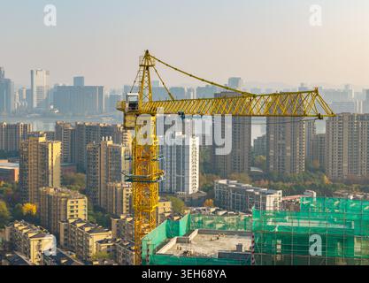 Grue à tour jaune vibrante travaillant sur un projet de construction dans une ville moderne animée Banque D'Images