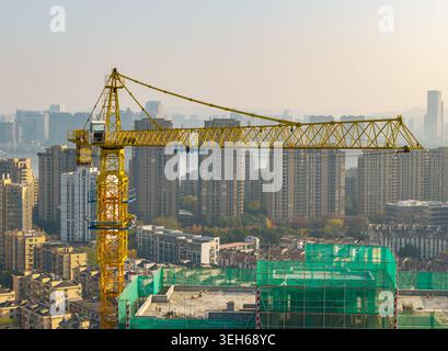 Grue à tour jaune vibrante travaillant sur un projet de construction dans une ville moderne animée Banque D'Images