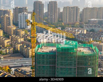 Grue à tour jaune vibrante travaillant sur un projet de construction dans une ville moderne animée Banque D'Images