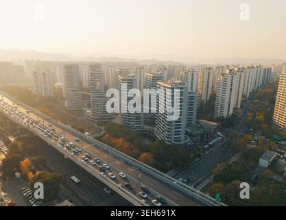 Vue sur la ville animée avec une autoroute surélevée éprouvant des embouteillages, entouré de bâtiments contemporains imposants et d'arbres dans une lumière chaude Banque D'Images