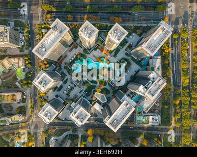 La vue aérienne capture un complexe résidentiel urbain moderne avec des tours de grande hauteur, des piscines sinueuses et du feuillage d'automne Banque D'Images