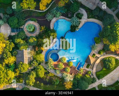 Vue aérienne des vastes piscines du complexe entourées de divers arbres et de sentiers sinueux par un matin ensoleillé Banque D'Images