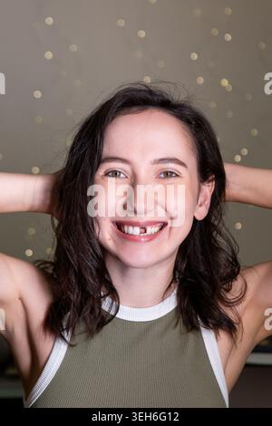 Une femme mature se tient seule montrant un sourire sans sa dent de devant. Elle exprime des émotions liées à son état dentaire. L'arrière-plan indique Banque D'Images