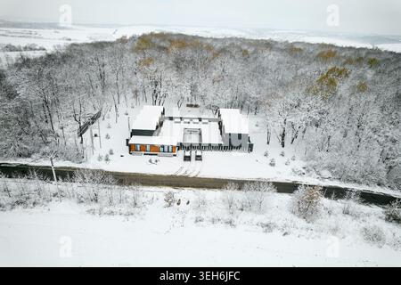 Développement de logements contemporains recouverts de neige fraîche en hiver. Vue drone de maisons en bois minimalistes avec cour intérieure et piscine, cadre de nature rurale, concept immobilier premium Banque D'Images