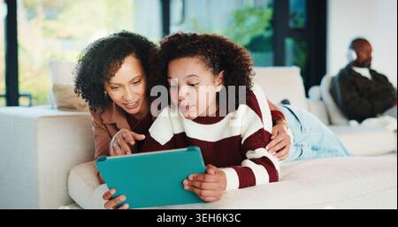 Maman, enfant ou jouer avec une tablette sur un canapé pour se divertir, se lier ou s'abonner en ligne à la maison. Mère, fille ou enfant couché avec la technologie ou Banque D'Images