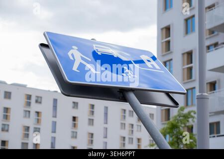 Panneau de signalisation bleu pour les piétons, les cyclistes et les véhicules installés devant des immeubles d'appartements contemporains dans une distri urbaine moderne Banque D'Images