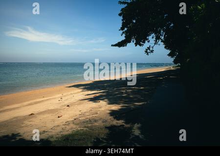Plage tropicale à Sanur, Bali avec littoral océanique calme, ombres douces et ciel bleu clair. Paysage balnéaire paisible, voyage d'été et arrière-plan de vacances sur l'île. Photo de haute qualité Banque D'Images