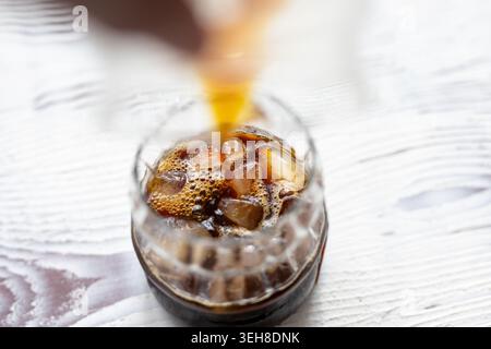 Gros plan du café glacé rafraîchissant versé dans un verre rempli de glaçons Banque D'Images